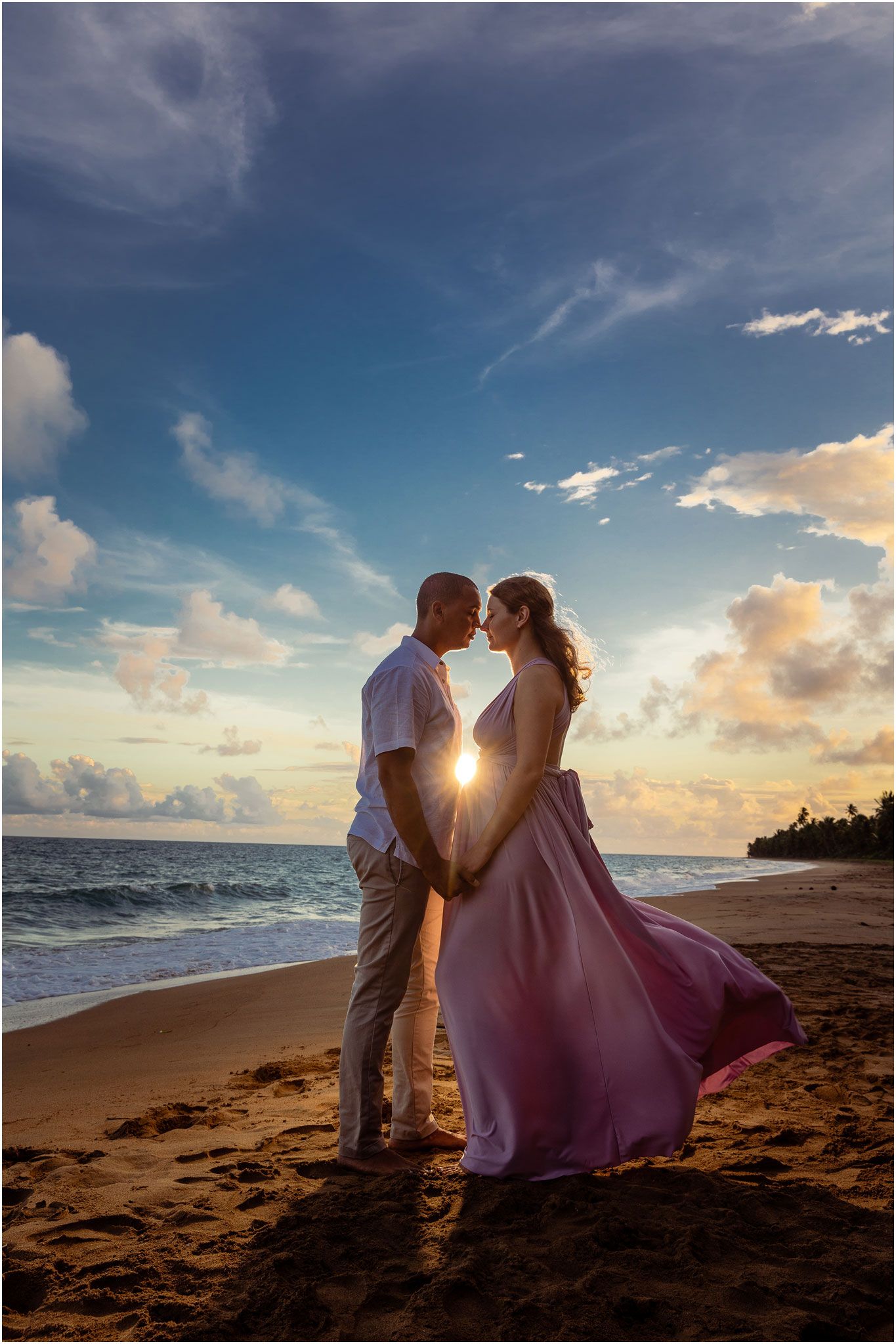 Silhouetted couple share intimate moment on beach at golden sunset.