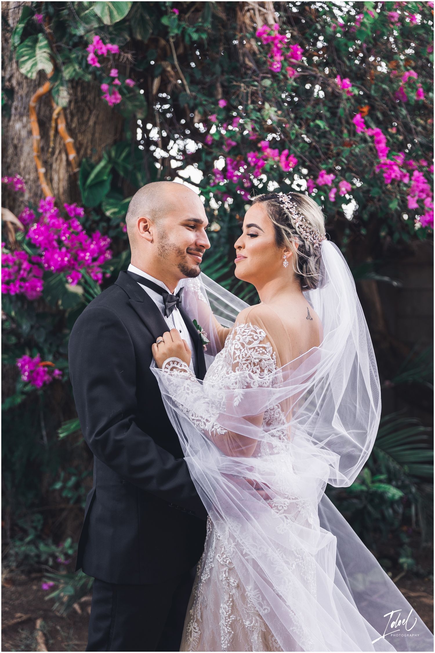 A romantic wedding portrait with the couple embracing under flowering branches.