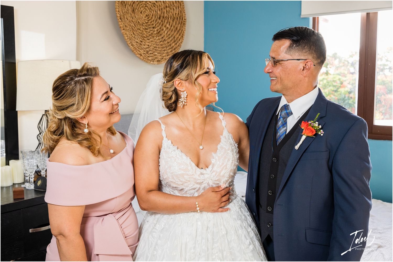 Wedding party sharing joyful moment in room with blue accent wall and woven wall decor.