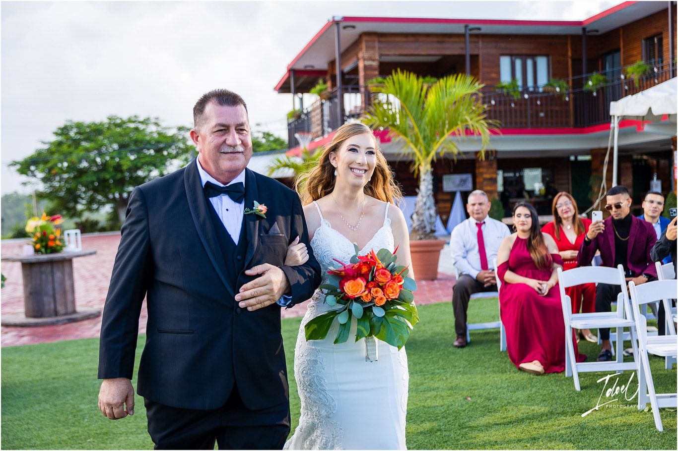 Wedding celebration on a scenic outdoor venue with palm trees and rolling hills in the background.