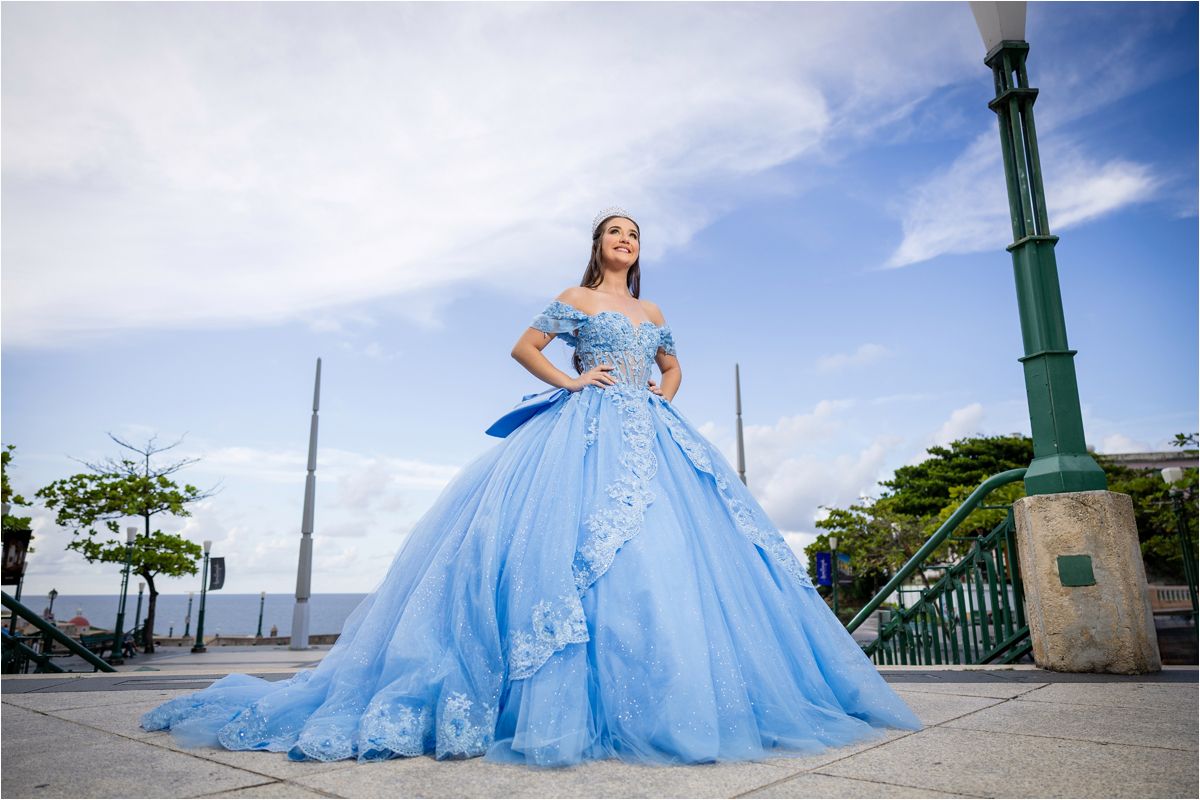A stunning powder blue quinceañera dress with full tulle skirt photographed at a scenic waterfront location.