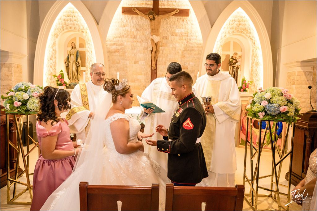 Catholic wedding ceremony taking place before ornate gothic arches and a wooden crucifix.