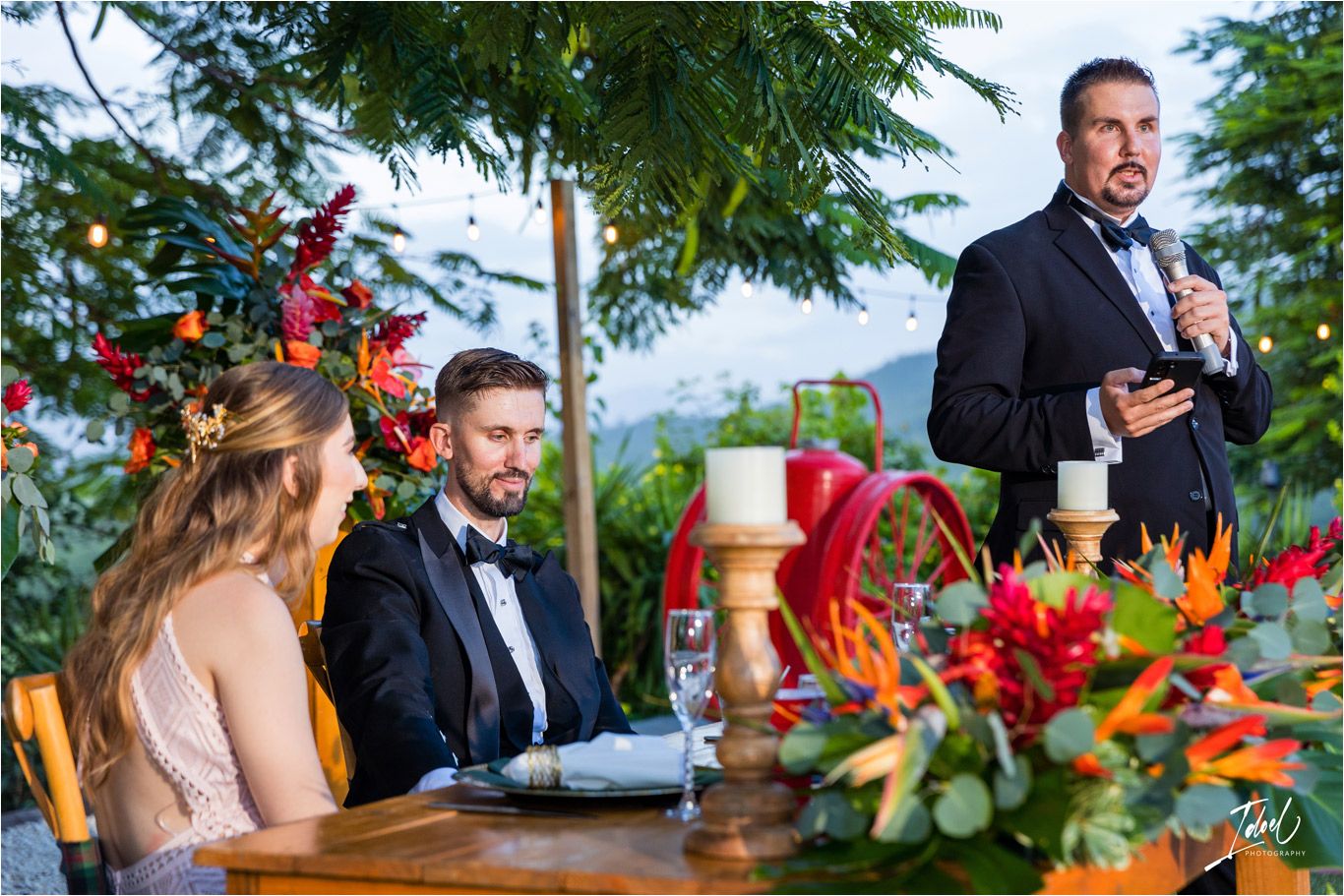 Wedding reception table decorated with vibrant tropical flowers and greenery.