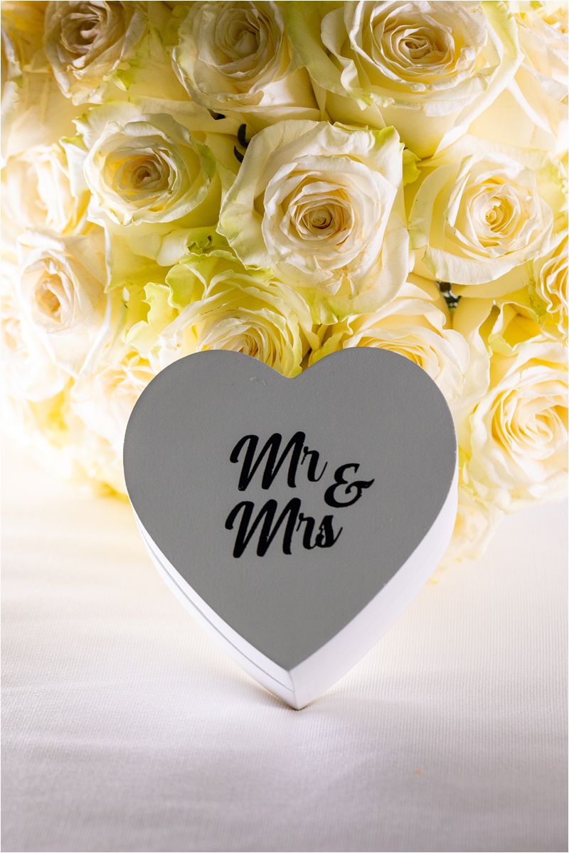Heart-shaped 'Mr & Mrs' sign displayed against a backdrop of cream colored roses.