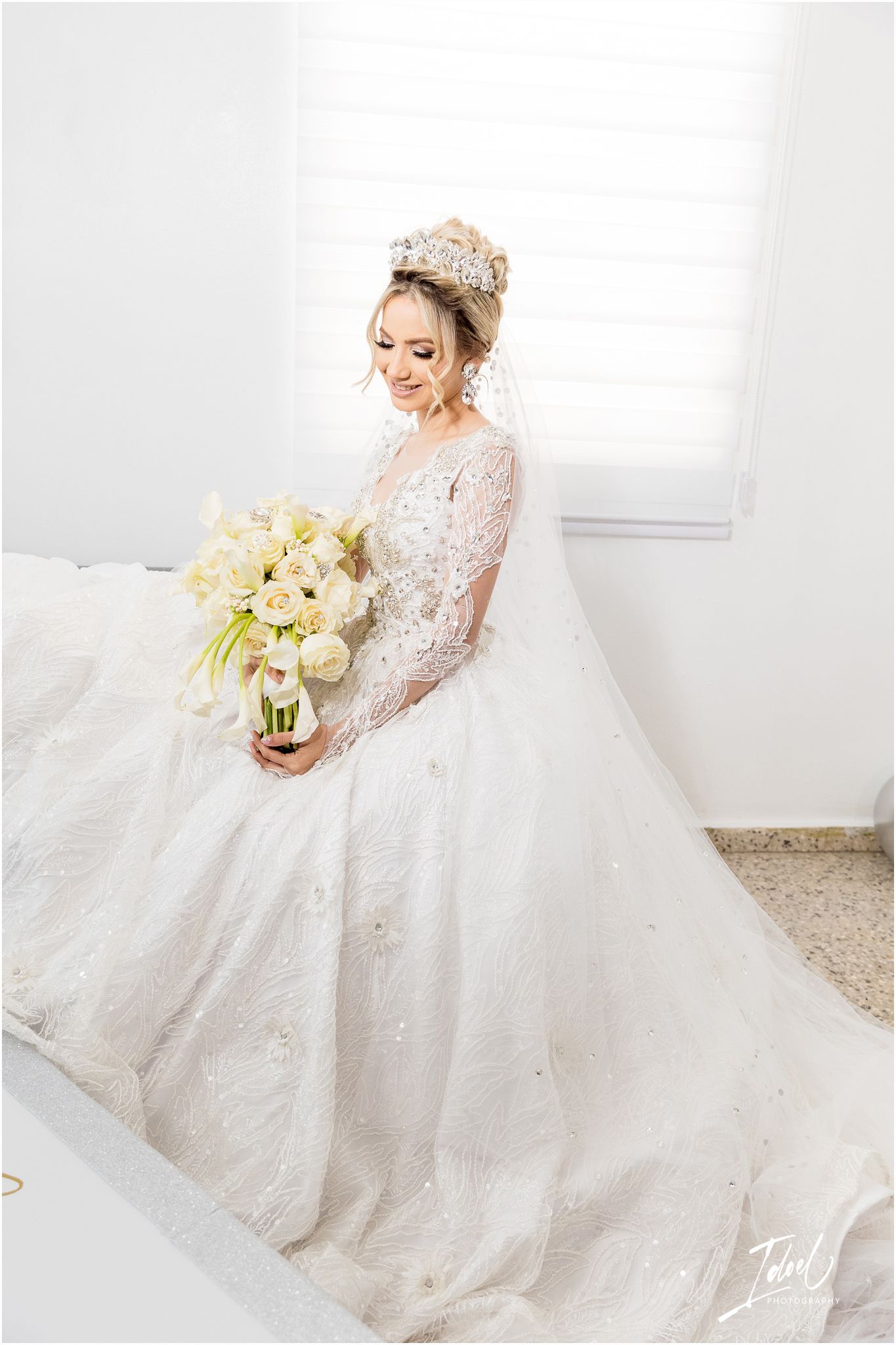 Stunning bride in embellished ballgown holding white and cream floral bouquet.