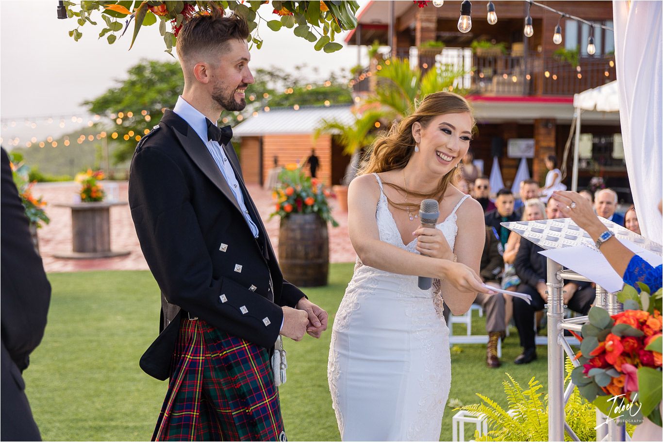 A joyful celebration moment at an outdoor wedding with Scottish dress elements and beautiful floral decorations.