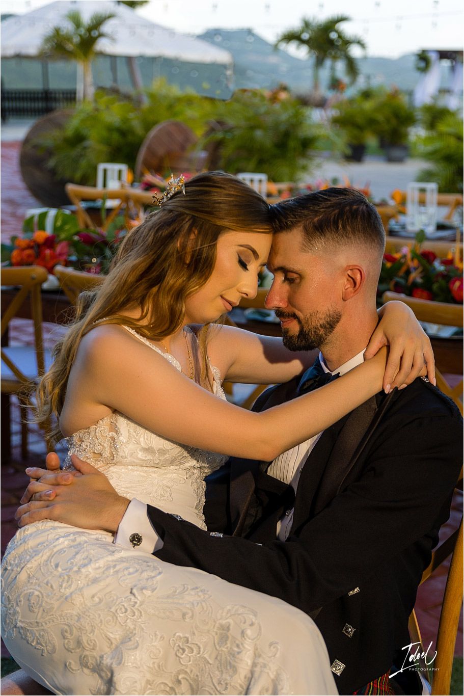 A tender moment between newlyweds at sunset with tropical mountains in the background.