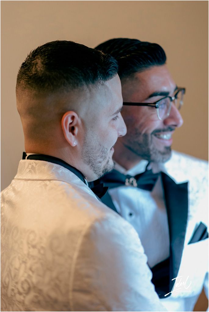 Two grooms in formal wedding attire share a joyful moment during their special day.