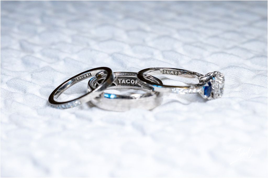 Three wedding rings photographed on white textured surface with blue accent stone.