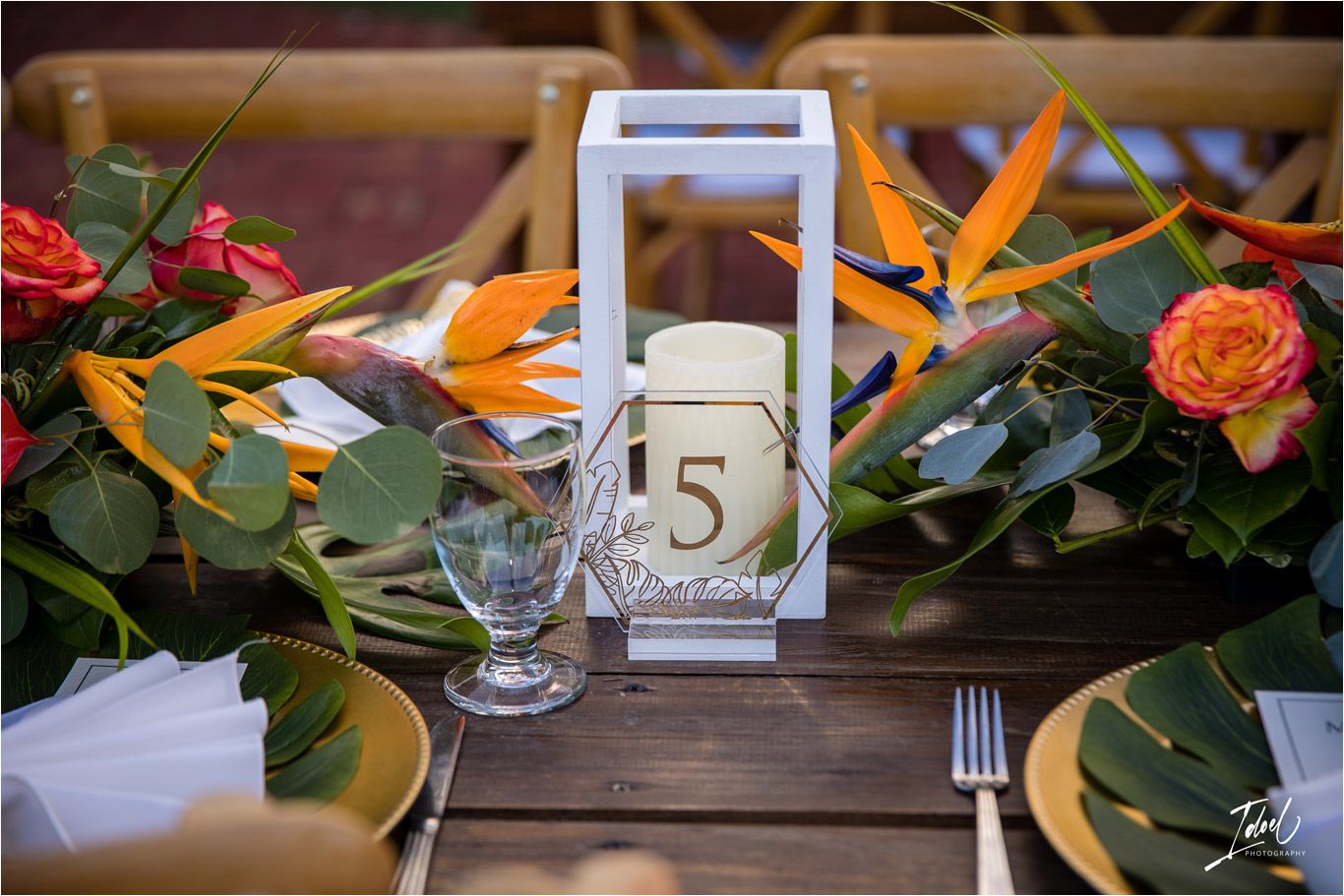 Wedding table setting with birds of paradise flowers and a white lantern table number display.