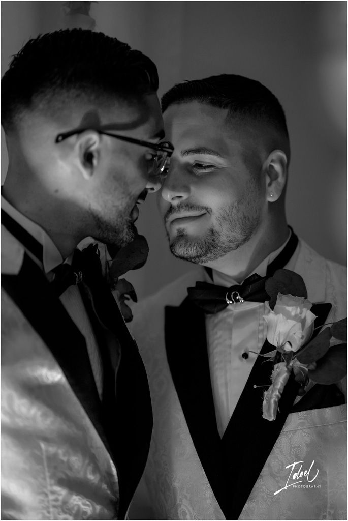 A romantic black and white portrait of a couple in formal attire with boutonnières during their wedding celebration.