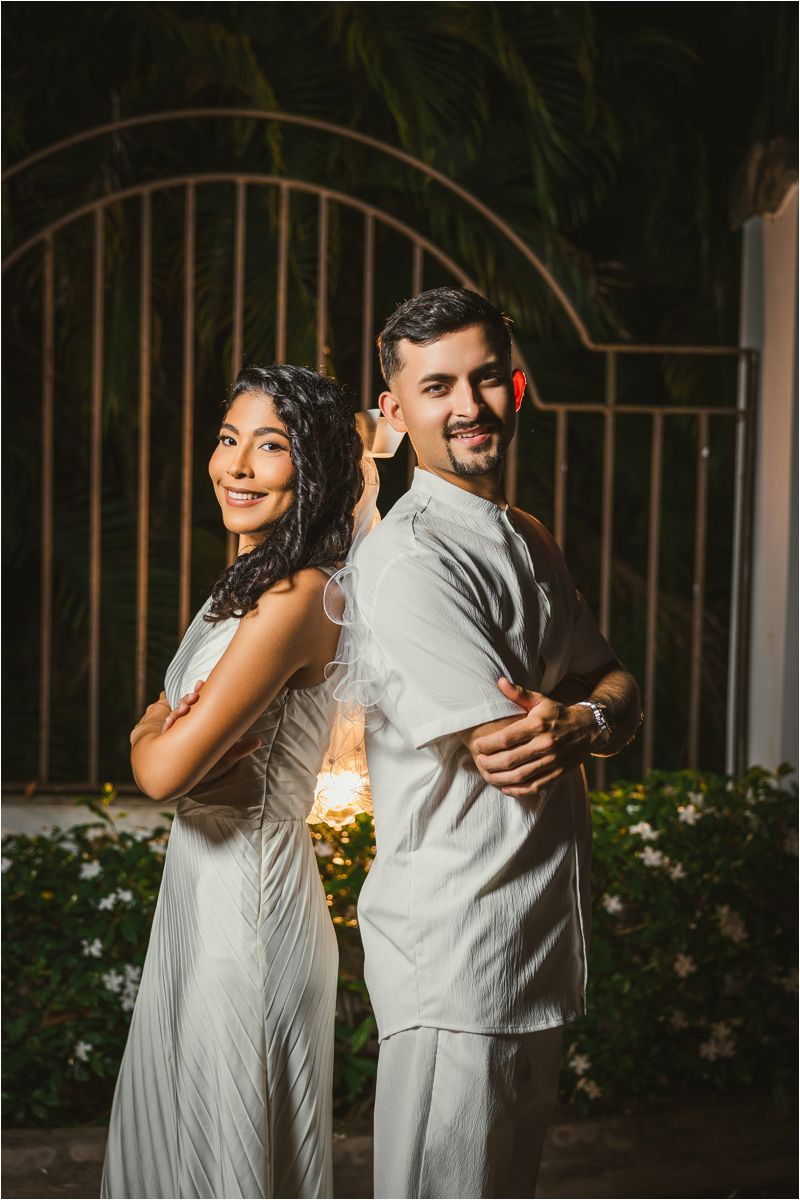 A couple in light gray attire dances and laughs together during an evening celebration.