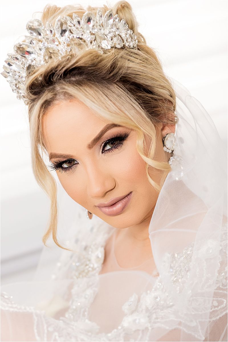 A bride wearing an ornate veil and tiara smiles in a series of close-up wedding portraits with soft lighting.