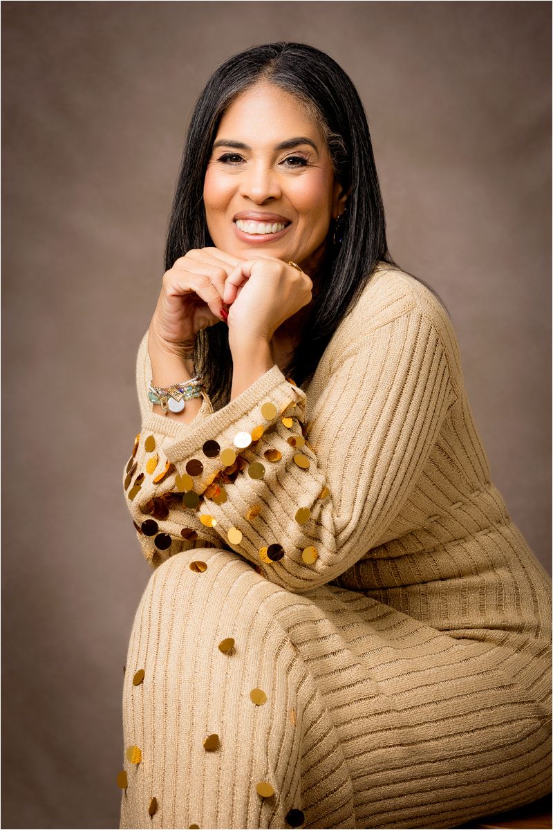 Professional portrait of someone wearing a cozy beige knit cardigan with brown polka dots against a neutral background.