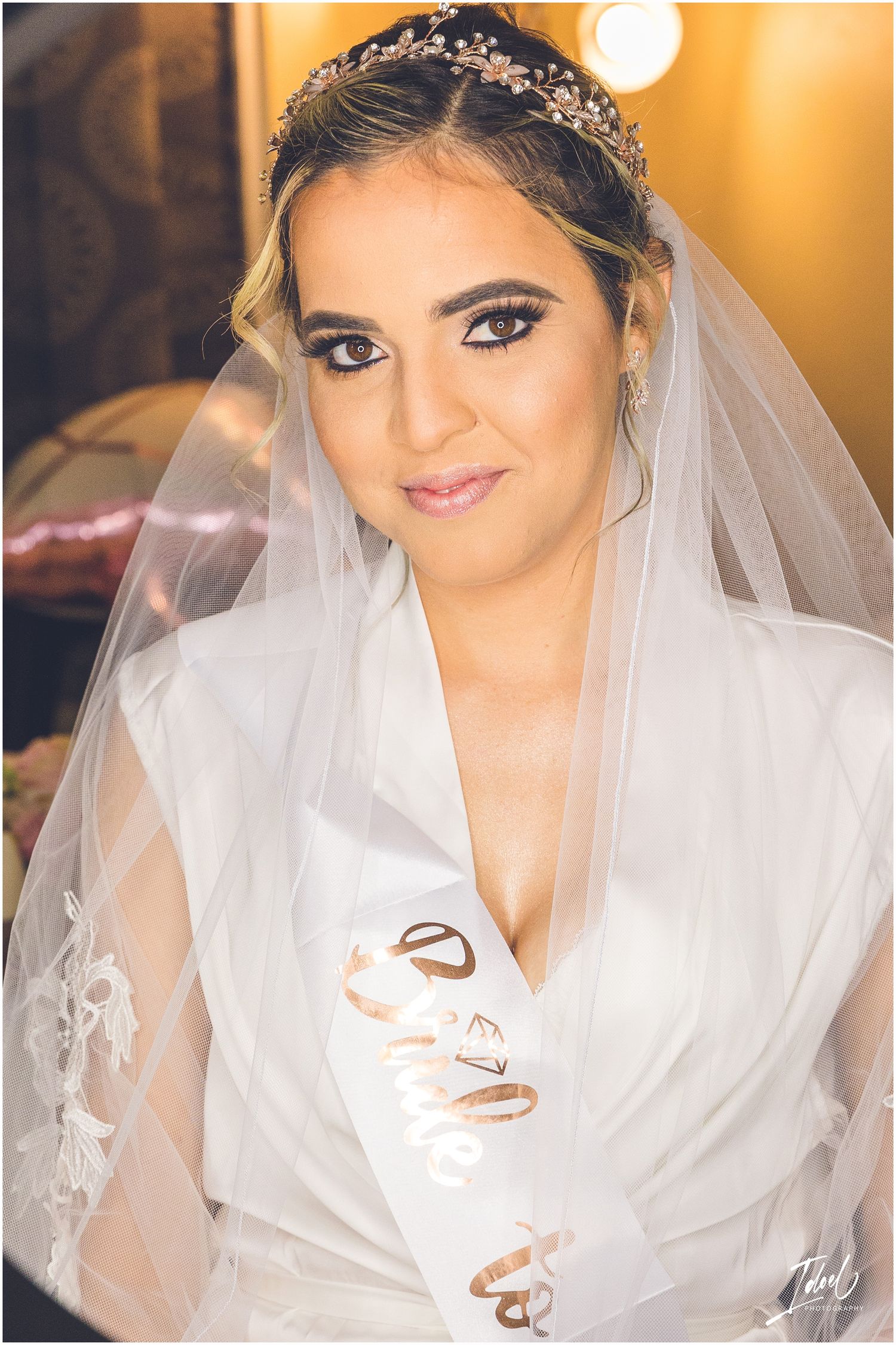 Bride wearing a delicate crystal headpiece and white robe while getting ready on her wedding day.