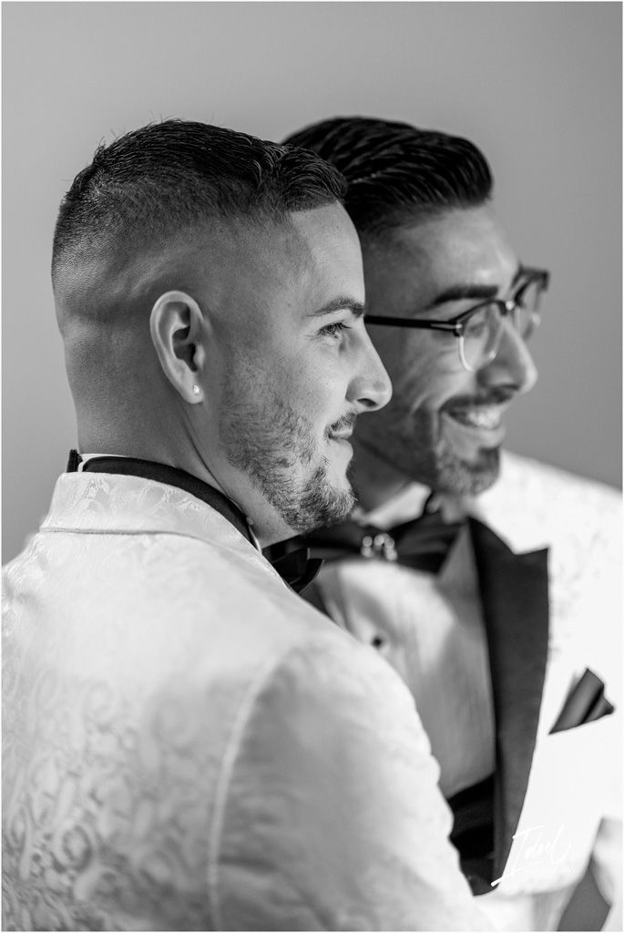 Black and white side profile photo of two smiling people in formal attire with bow ties and white shirts.