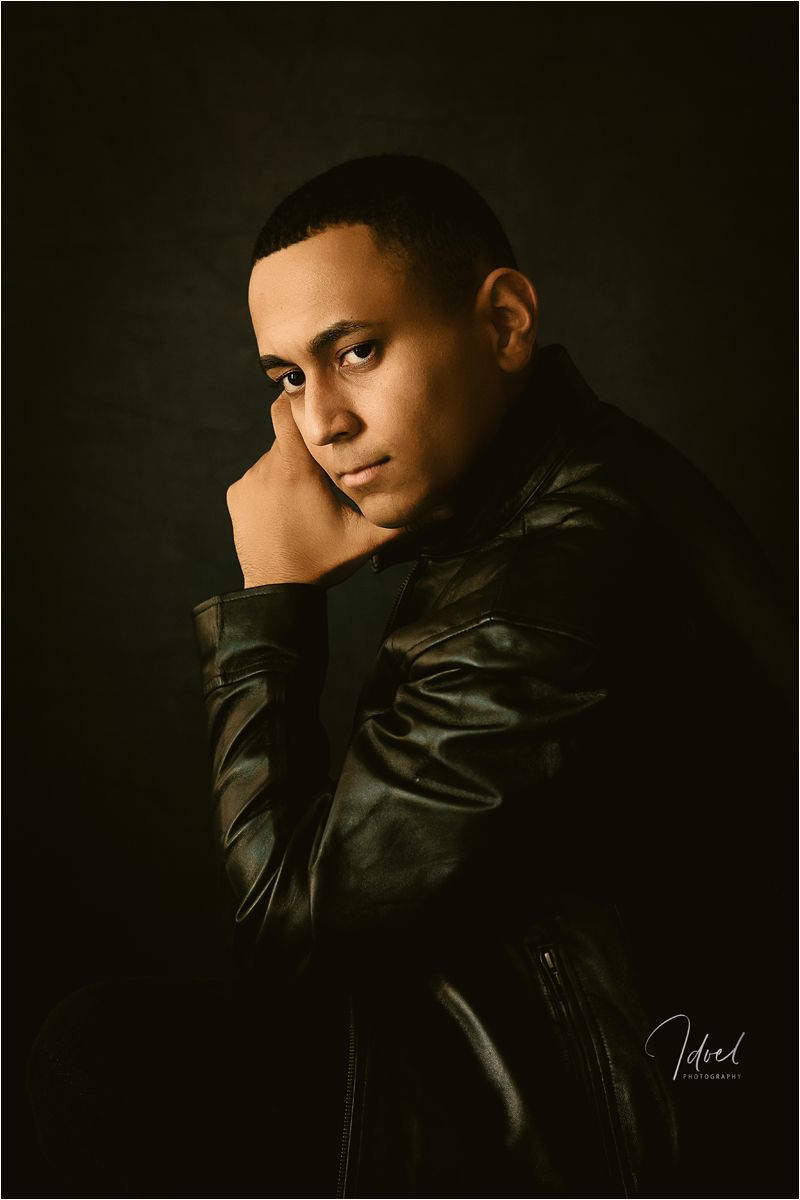 Dramatic low-key portrait series in dark lighting showing a figure in black leather jacket against shadowy background.