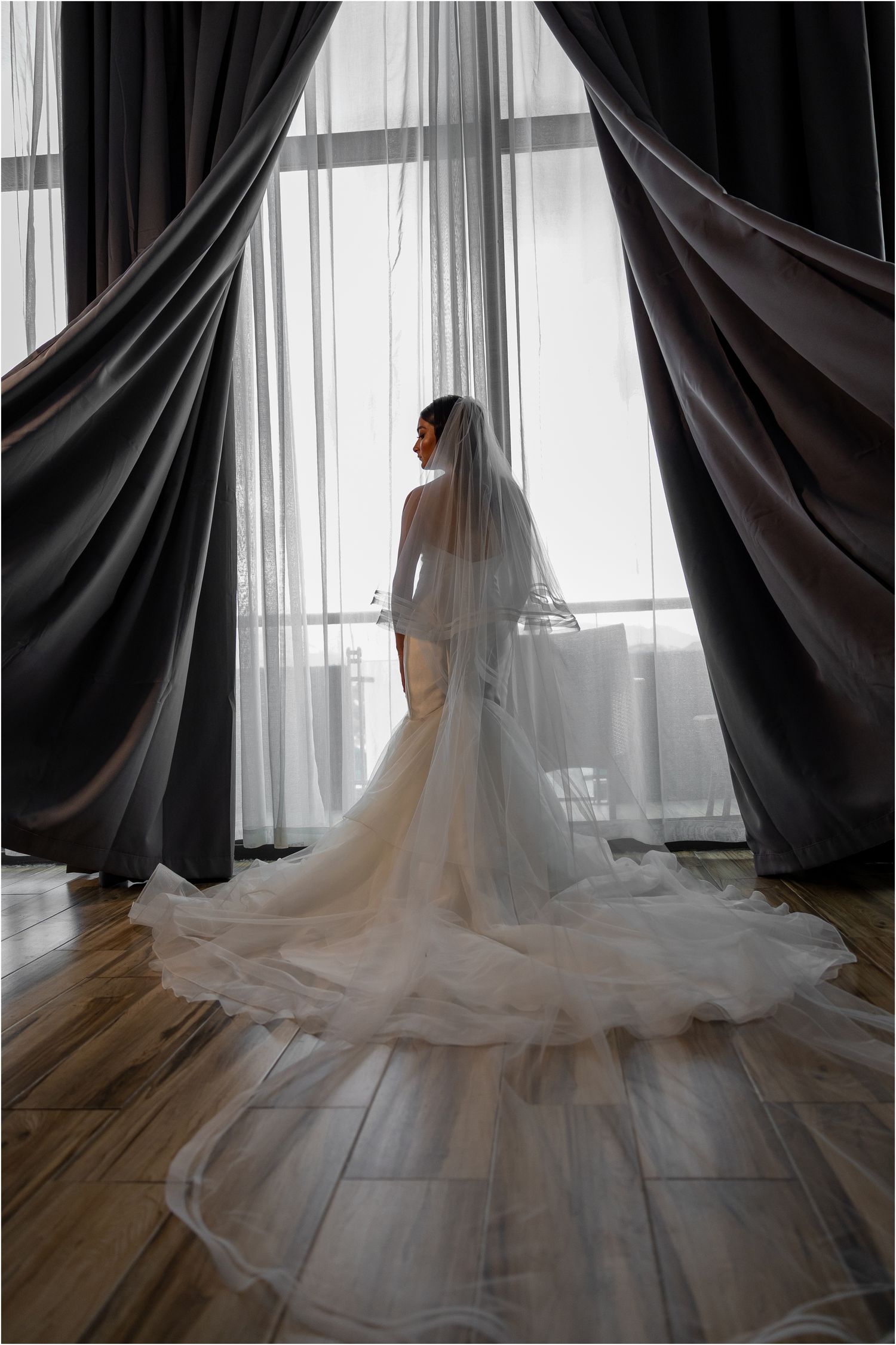Bride in a cathedral length wedding dress shown in a series of artistic poses against window light.