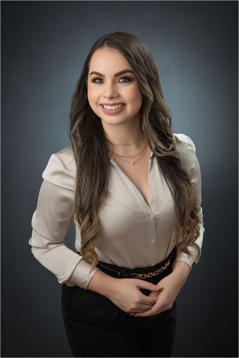 Professional studio portrait with dark backdrop featuring person in beige blouse and black pants in various poses.