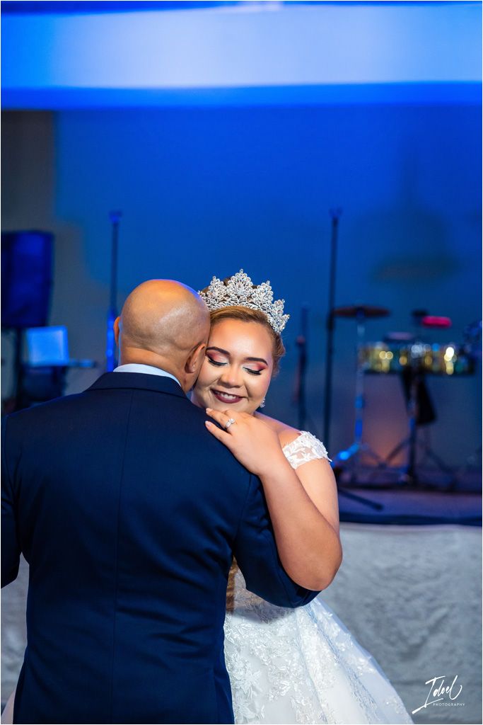 A tender moment shared during a wedding dance under blue lighting.