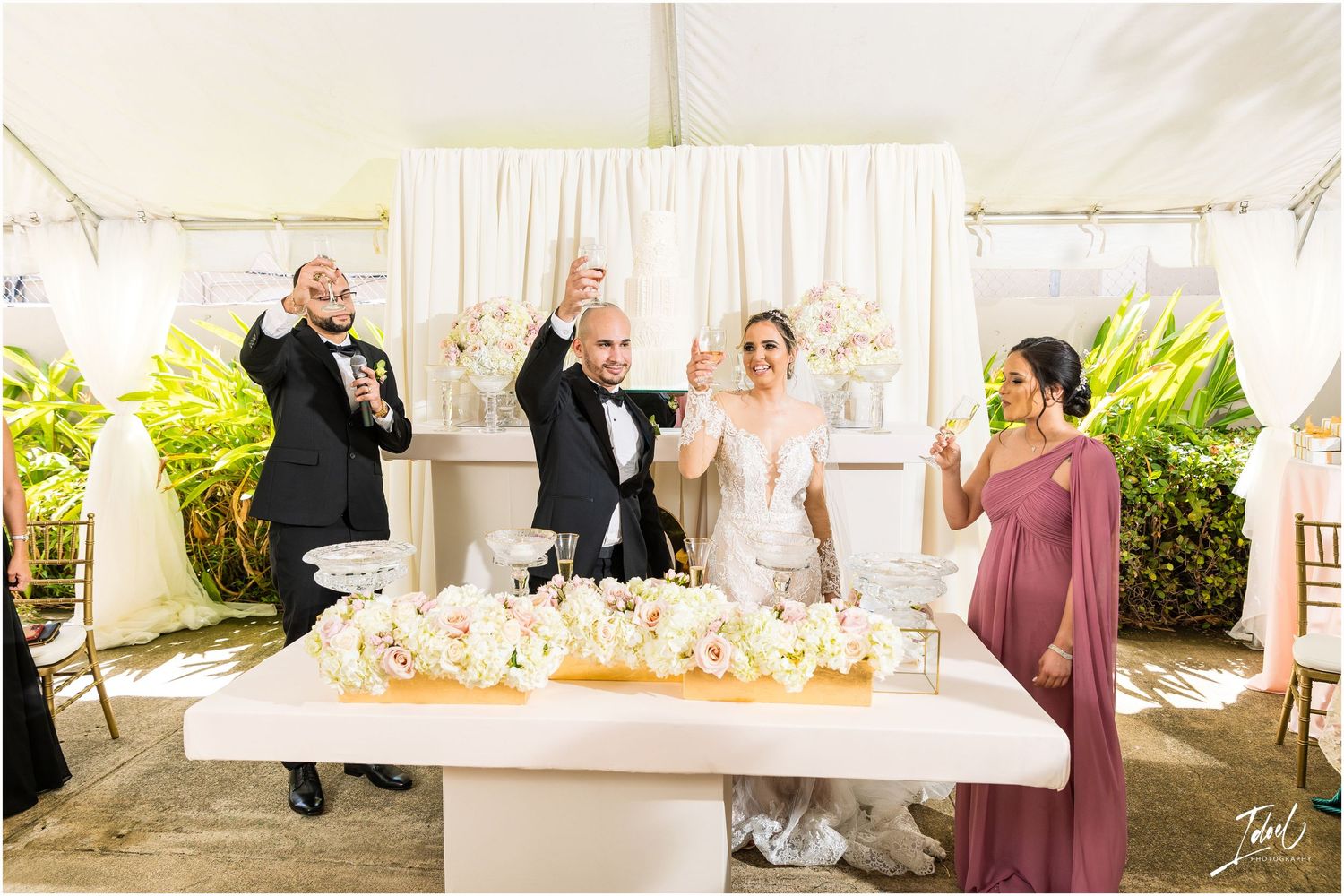 Wedding party celebrates with champagne toasts at an outdoor reception with elegant decor.