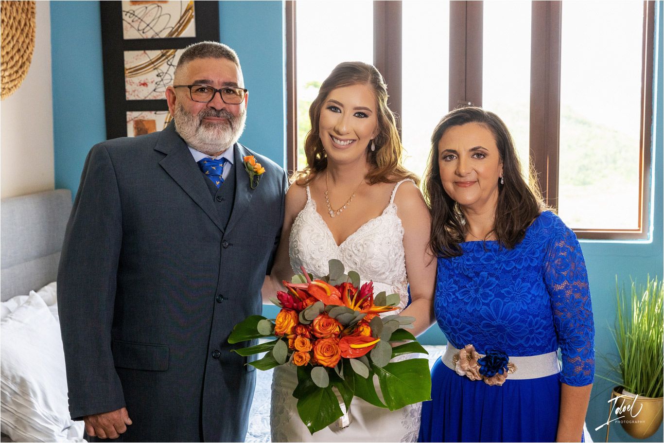 Wedding day family portrait with blue wall backdrop.