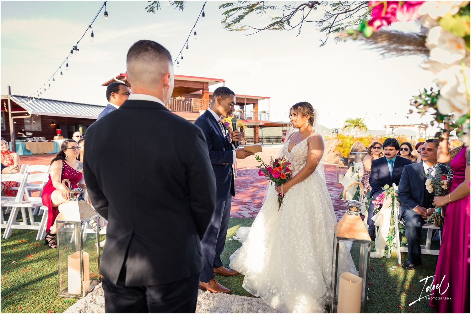 Outdoor wedding ceremony with lantern decorations and string lights at sunset.