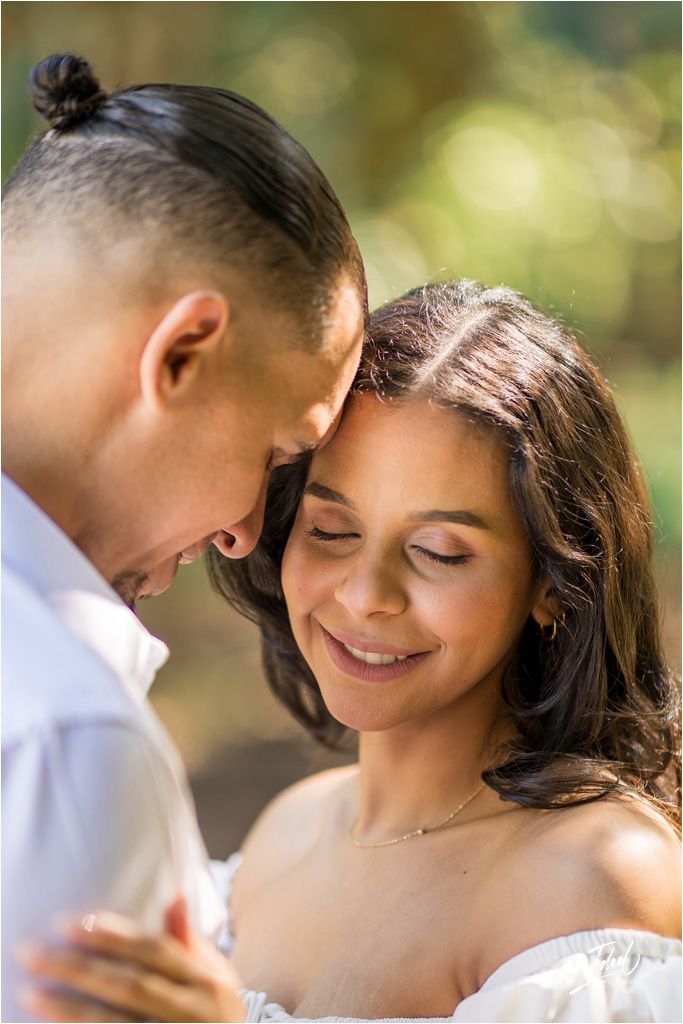 A romantic couple shares an intimate moment outdoors with soft natural lighting and gentle smiles.