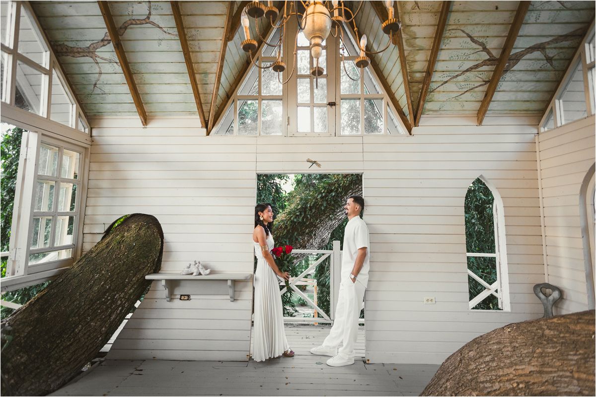 A rustic wooden gazebo with white painted walls and exposed beams creates a charming outdoor shelter space.