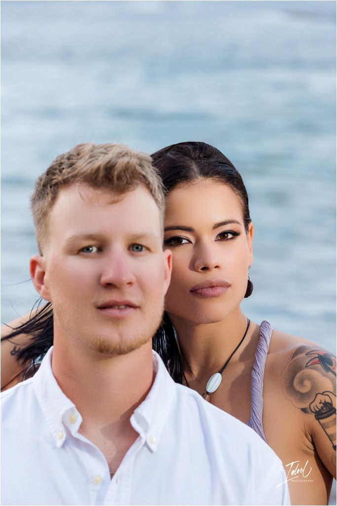 Portrait of couple against ocean background in white and gray attire.
