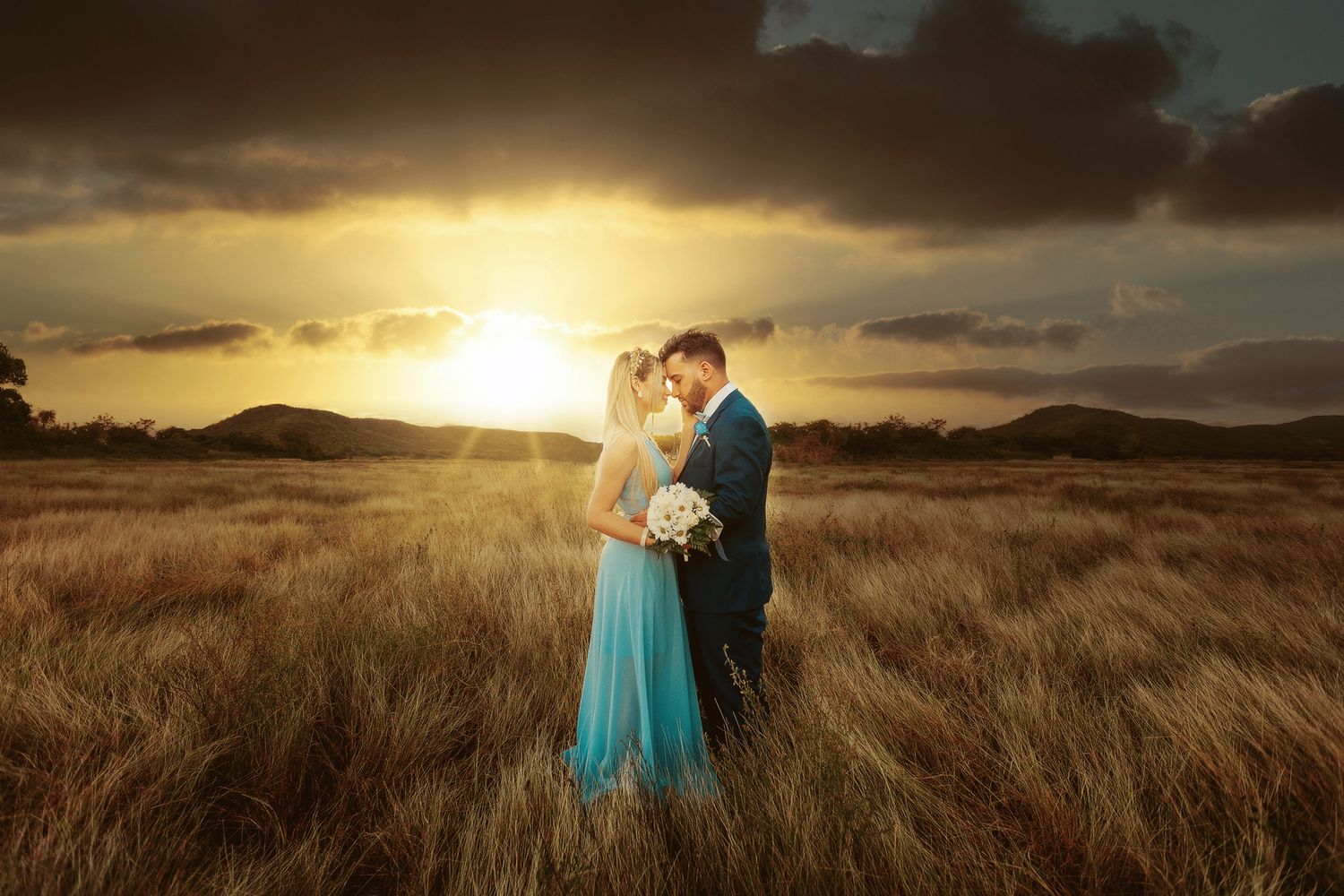 Sunset wedding photography in a golden field with dramatic sky.