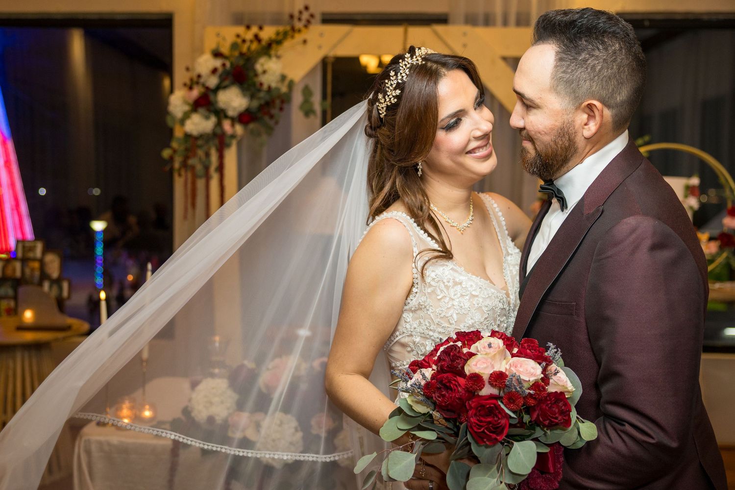 Wedding couple embracing under romantic lighting during evening reception.