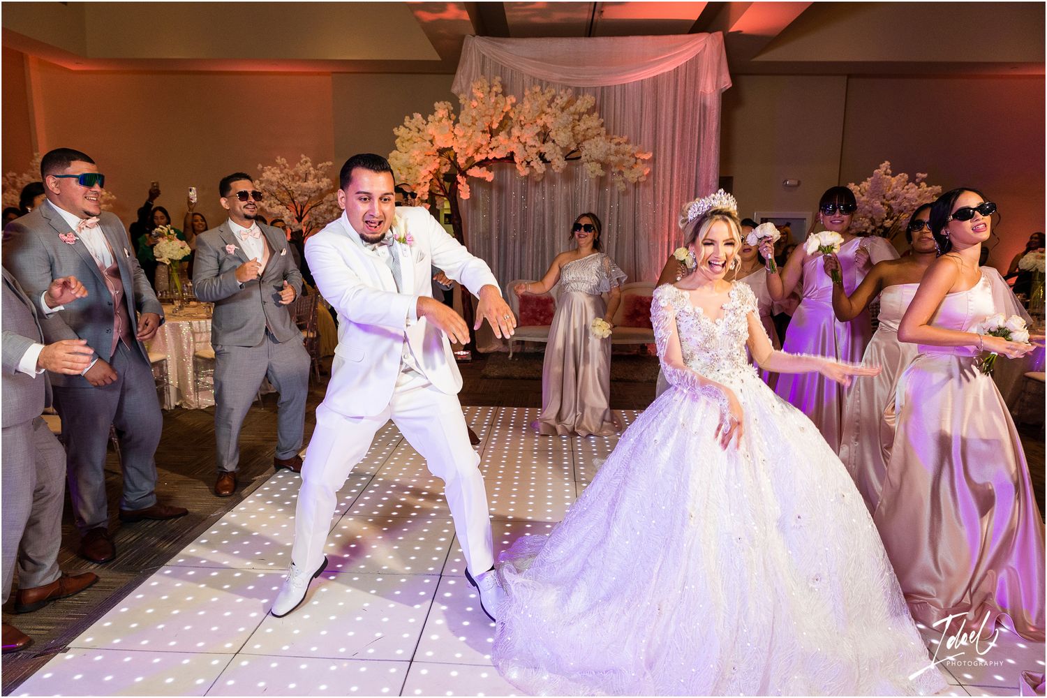 Couple shares an energetic dance moment at their wedding reception as guests cheer them on.