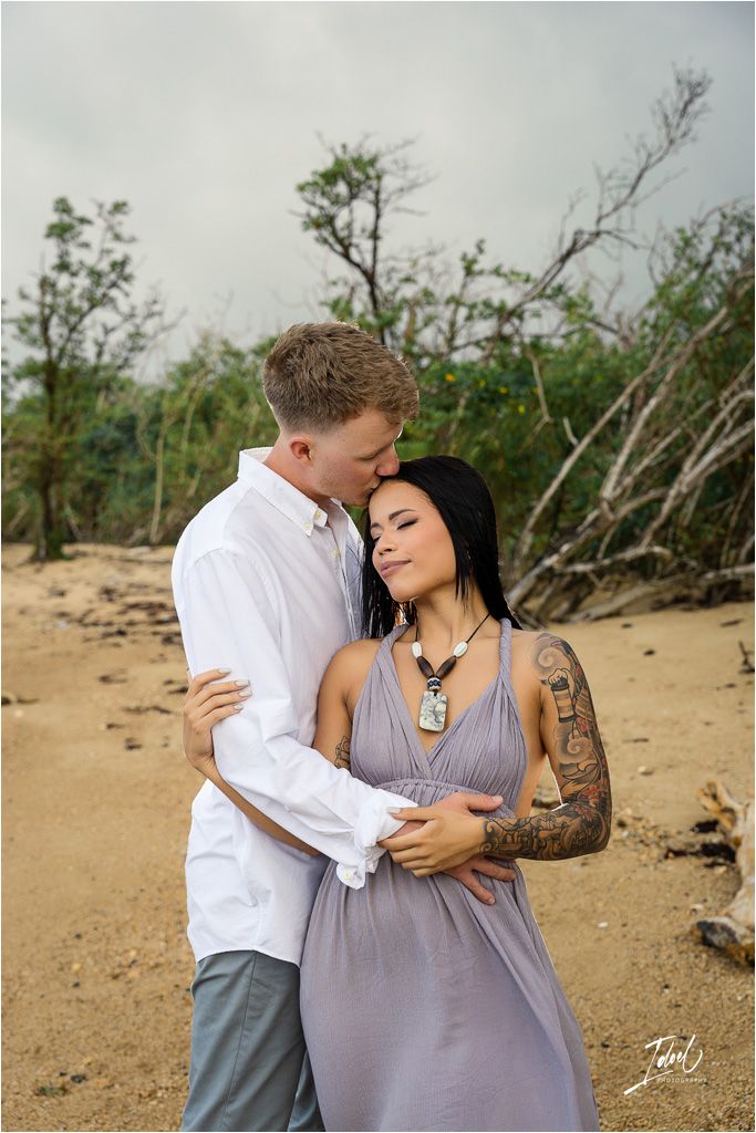 Intimate moment captured on secluded beach with natural backdrop.