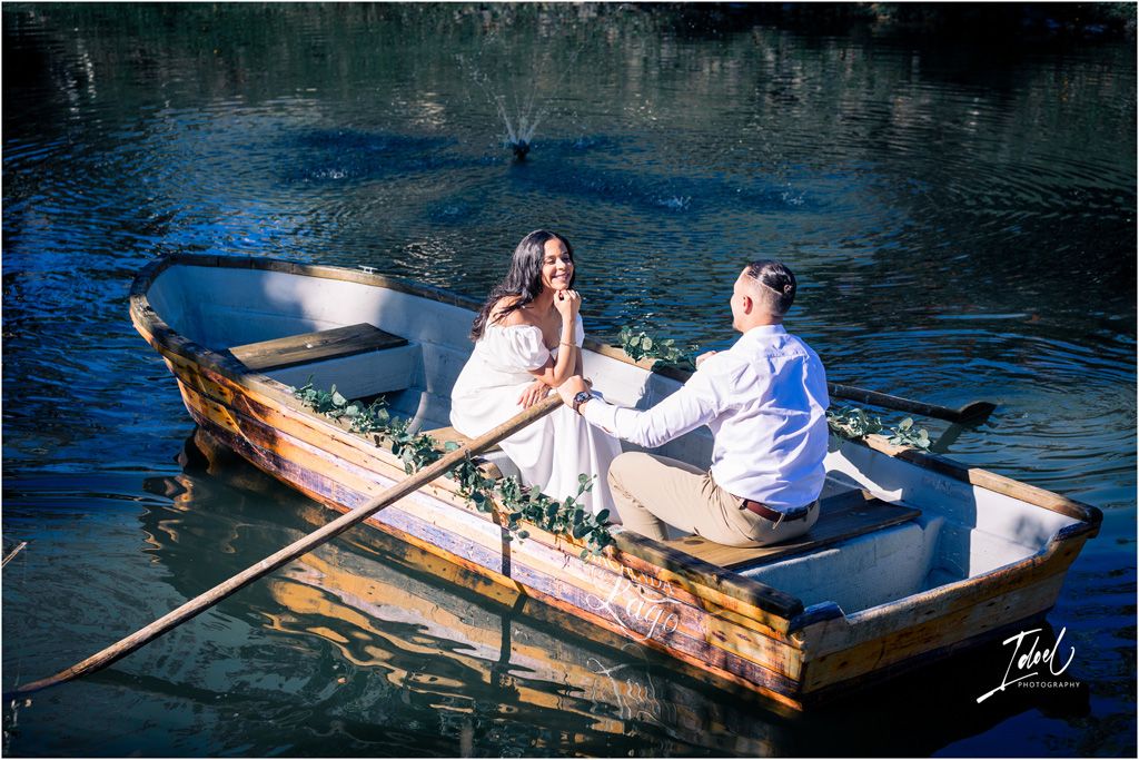 A couple enjoys a romantic wooden boat ride on tranquil blue waters during a sunny day.