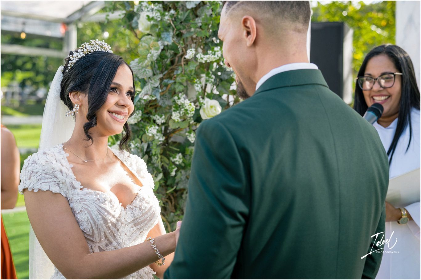 A couple shares an intimate moment during their outdoor wedding ceremony surrounded by lush greenery.