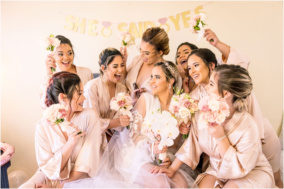 A group in matching pink robes laughs and celebrates together during a pre-wedding gathering.