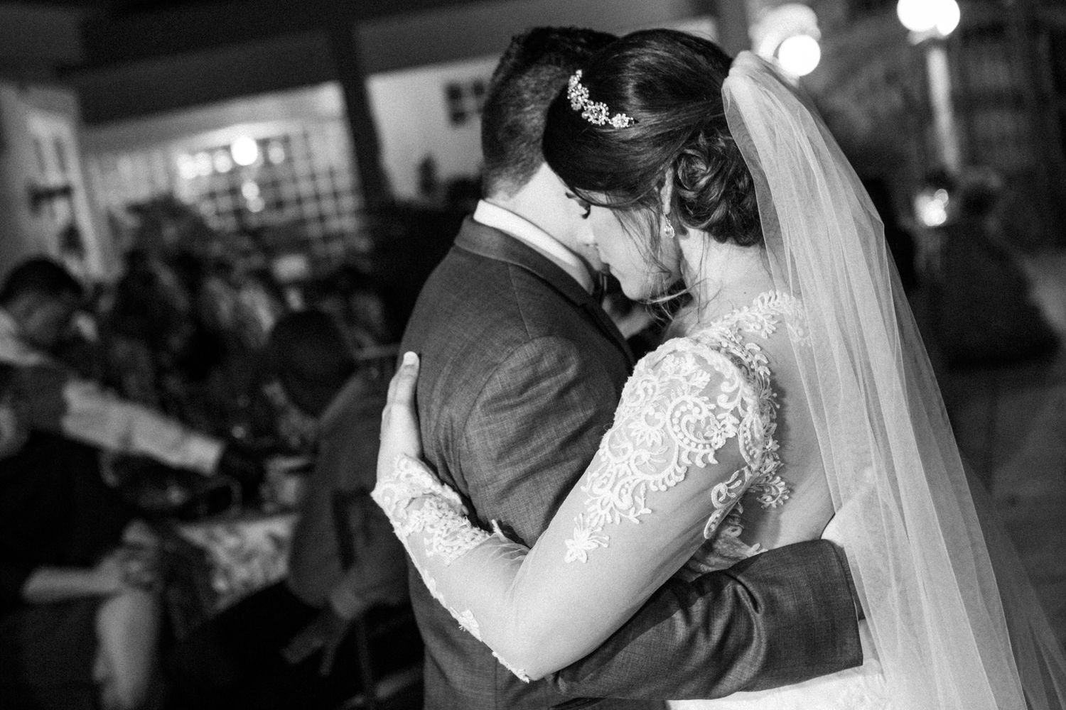 Wedding couple sharing first dance surrounded by reception guests.