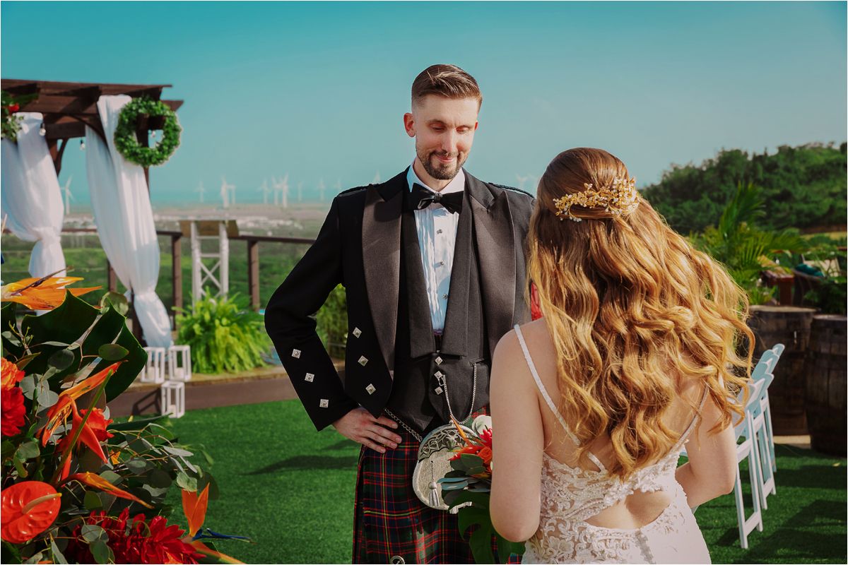 Wedding ceremony setup on green lawn with Scottish groom in traditional kilt.