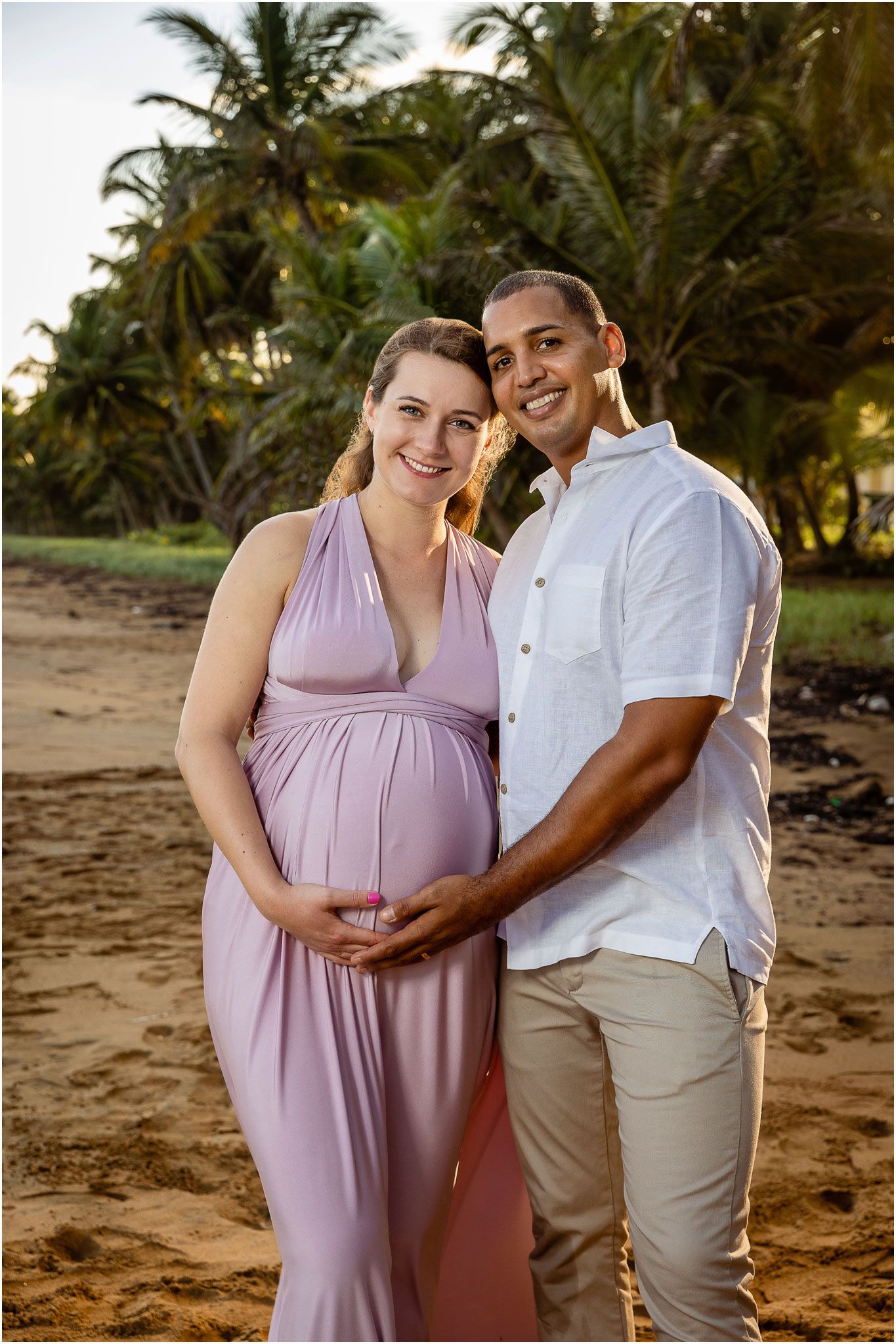 Palm-lined beach maternity portrait during golden hour.