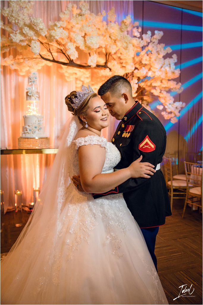 An intimate wedding reception moment with a couple dancing under illuminated cherry blossom decor.
