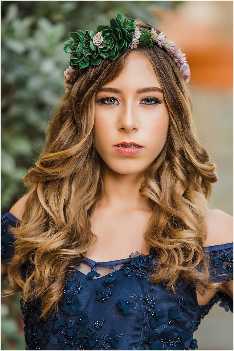 A navy blue lace dress adorned with floral details and paired with a green leaf crown creates an elegant look.
