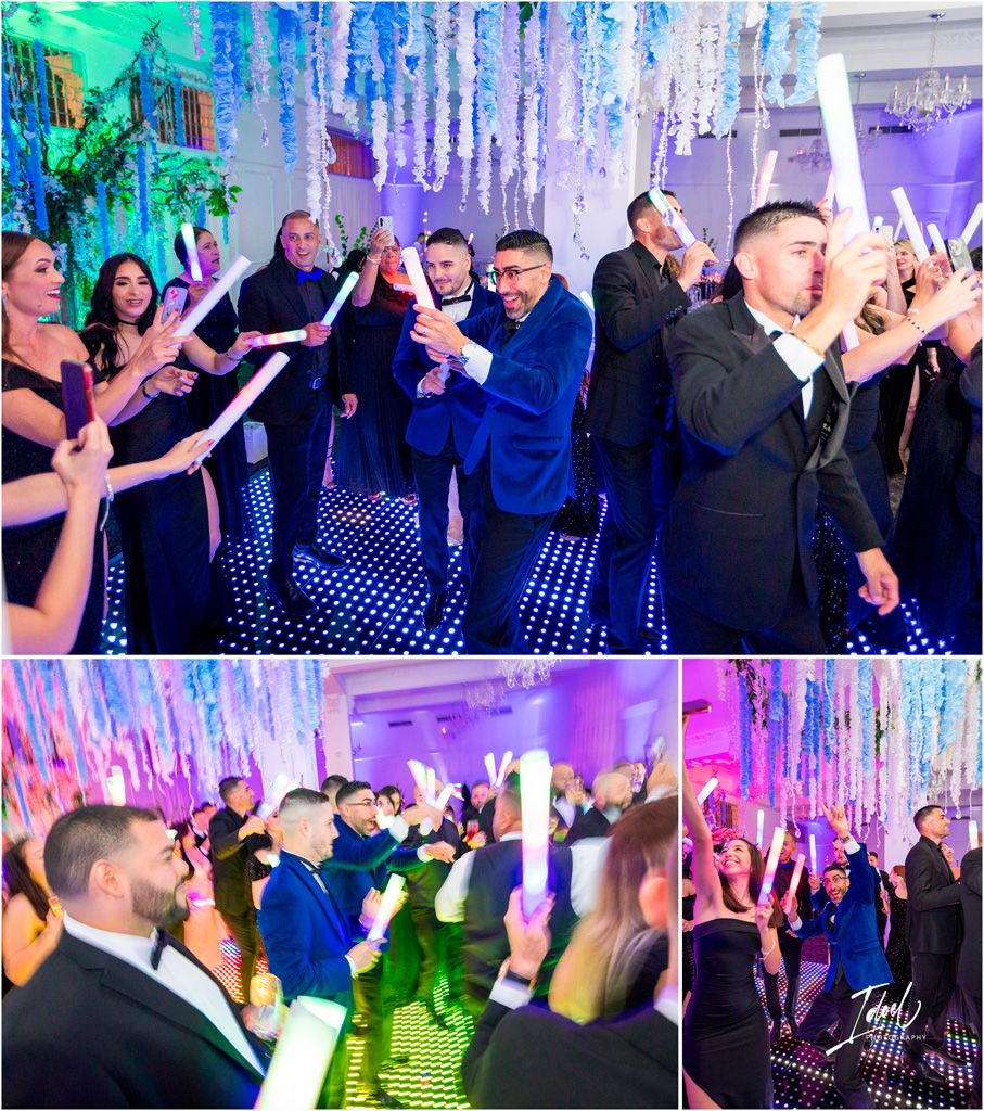 Party guests on a colorful LED dance floor raise glowing light sticks under blue and purple illuminated decorations.