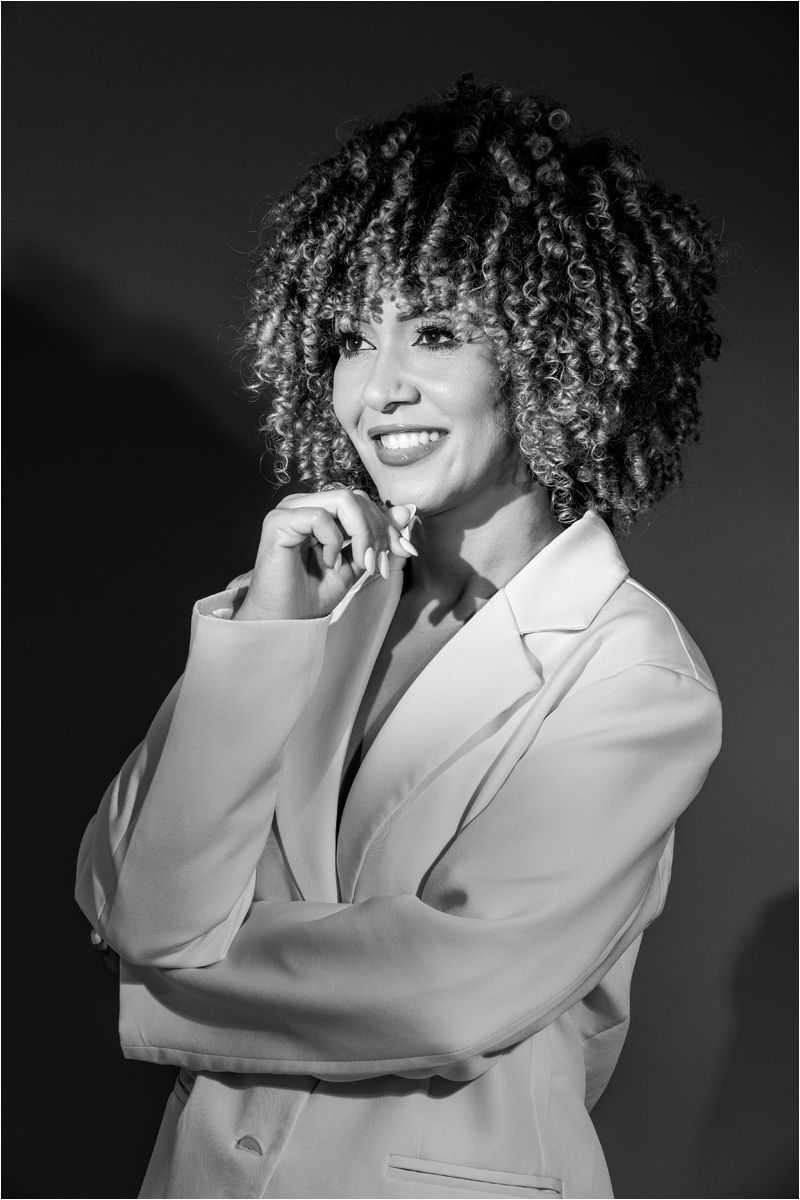 Artistic black and white portrait series showing a person with curly hair wearing a white blazer in dynamic poses.