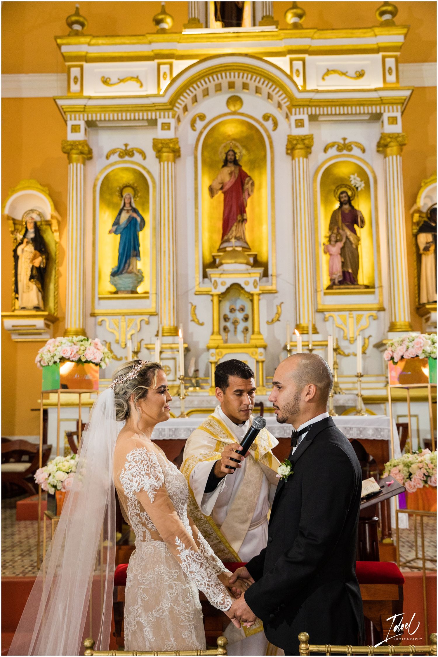 Wedding ceremony in front of ornate golden altar with religious iconography.