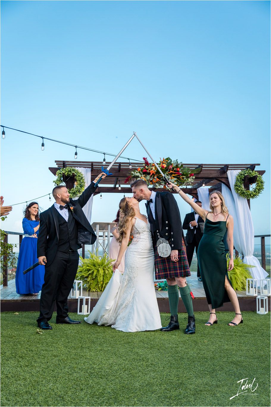 Wedding party celebrates on a rooftop venue with string lights and modern decor.