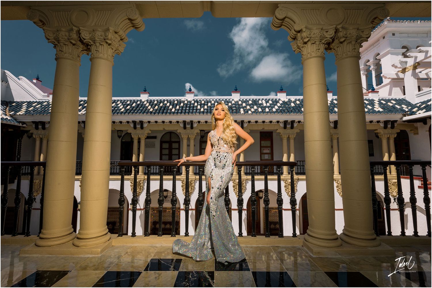 Sparkly silver gown shimmers against classical architecture and blue sky.