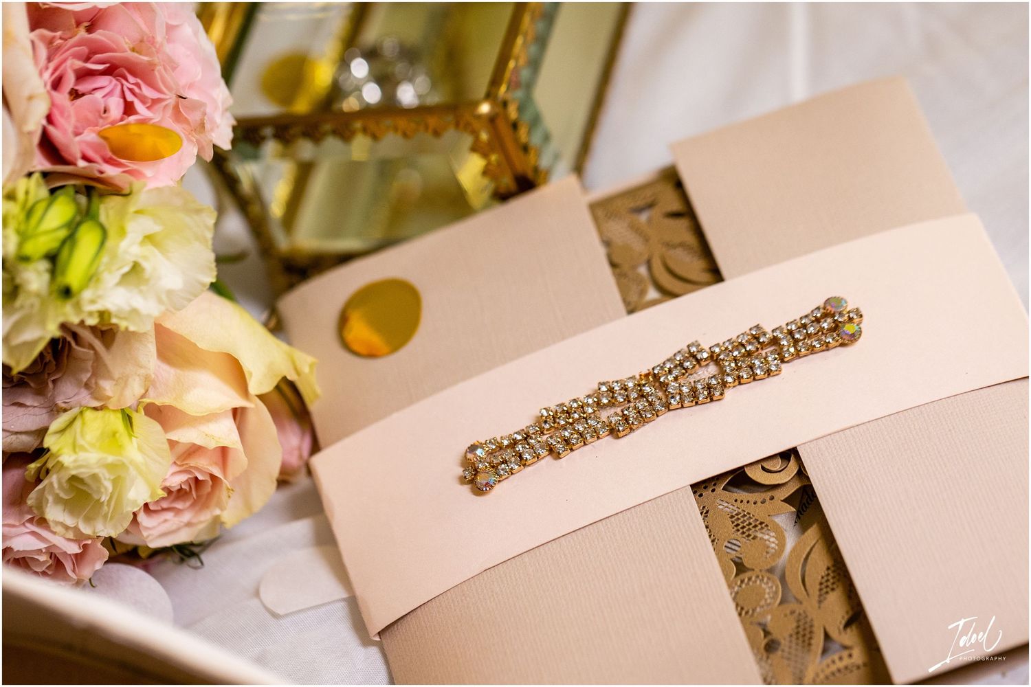 Wedding invitation details with blush roses and gold accents in soft lighting.