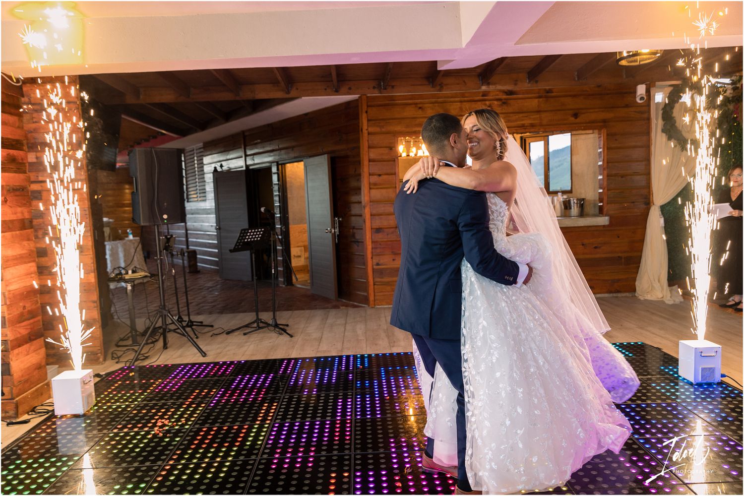 A romantic first dance moment on an LED dance floor with sparkling light pillars.