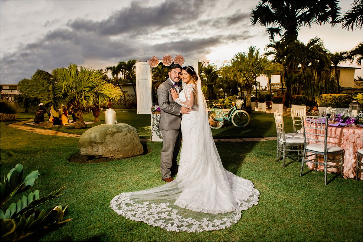 Romantic outdoor wedding ceremony and reception setup with floral decorations at sunset in a garden venue.